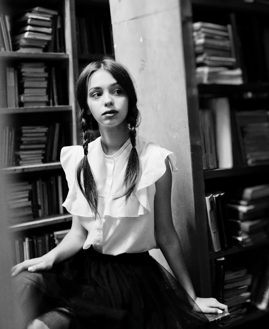 Student sitting among bookshelves